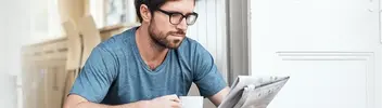 Mann liest gedruckte Tageszeitung