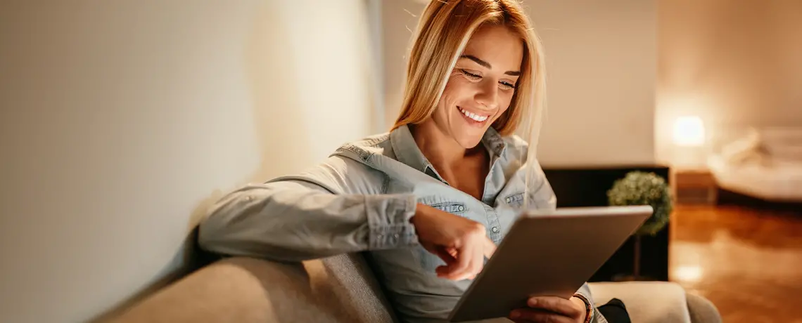 Frau sitzt auf dem Sofa mit einem Tablet in der Hand!